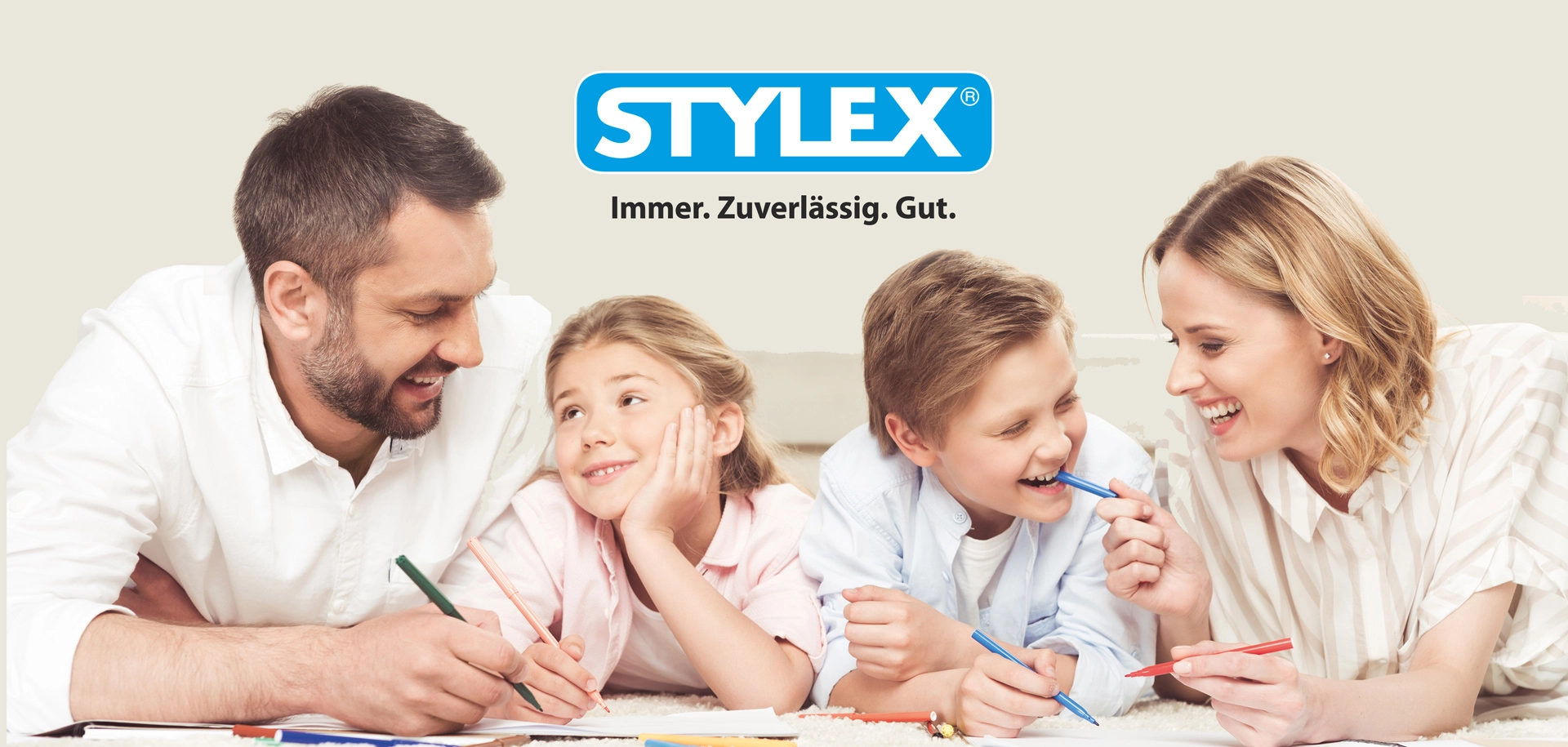 Eine Familie bestehend aus Mann, Frau, Junge und Mädchen mit Stiften in der Hand und Stylex Logo über ihnen